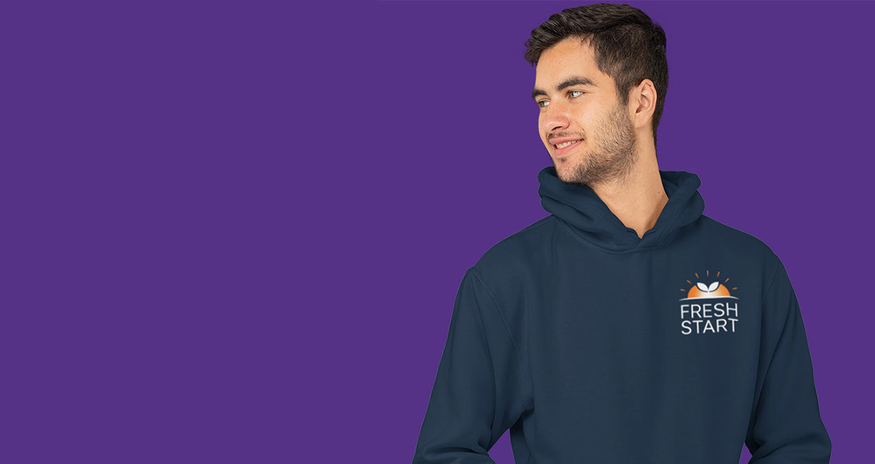 Man wearing a navy hoodie with 'Fresh Start' logo on a purple background